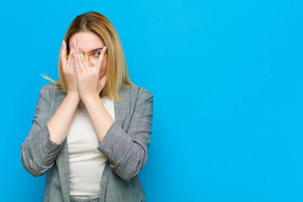 A woman hiding behind her hands